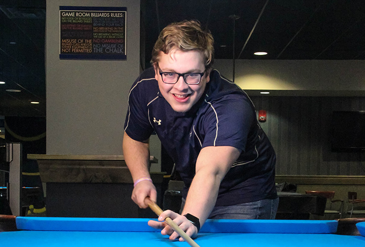 Student playing pool in the Roo Lounge