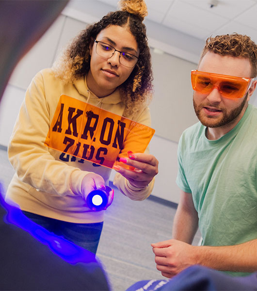 University of Akron criminal justice students examine evidence with a forensic light source and orange filter during a hands-on crime scene investigation lab.