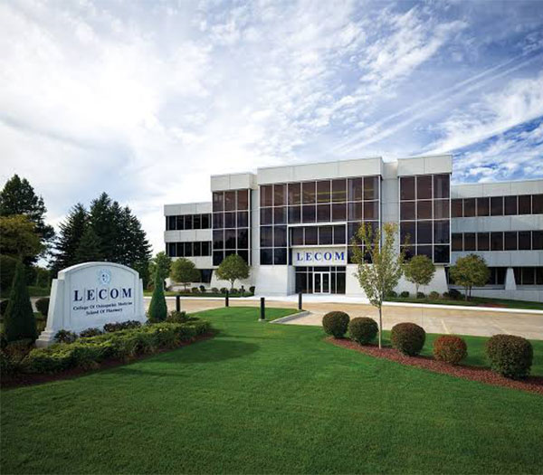 Exterior of the Lake Erie College of Osteopathic Medicine (LECOM) campus building with landscaped grounds and the LECOM entrance sign.