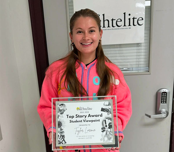 University of Akron student holds a Buchtelite Top Story Award certificate outside the Buchtelite newsroom.