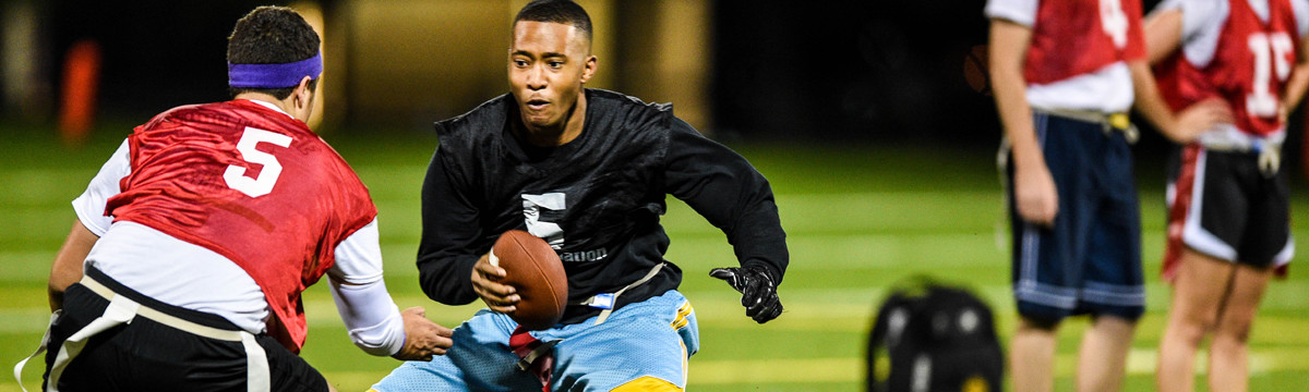 Students play intramural flag football on an outdoor field at night.