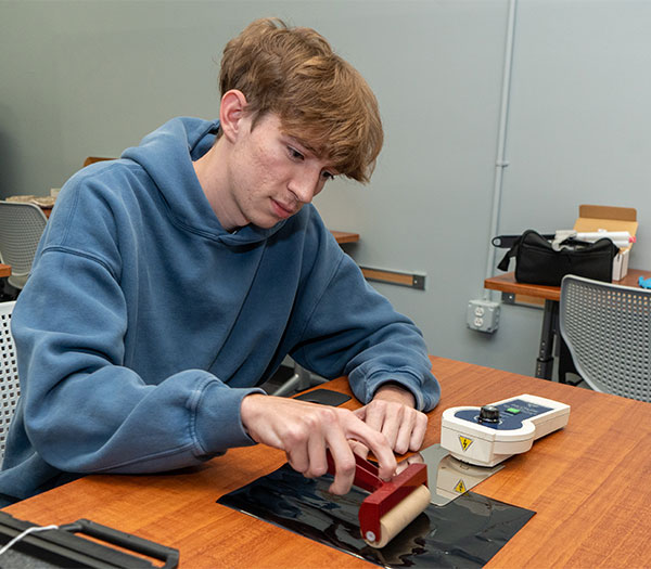 University of Akron student uses a roller to lift fingerprints from a surface during a forensic science lab activity.
