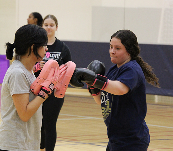 Two women boxing in a PGB class