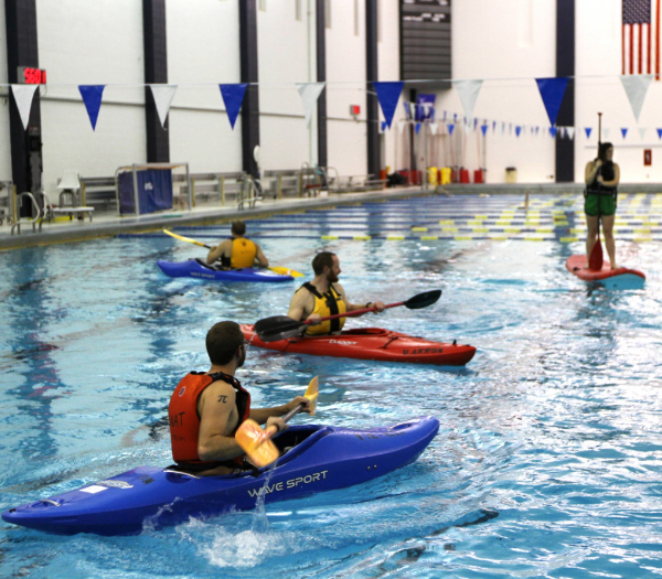 students kayaking and stand up paddleboarding indoors
