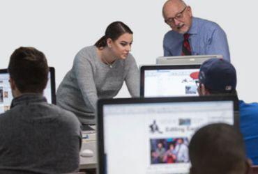 University of Akron student working on computers during business meeting.