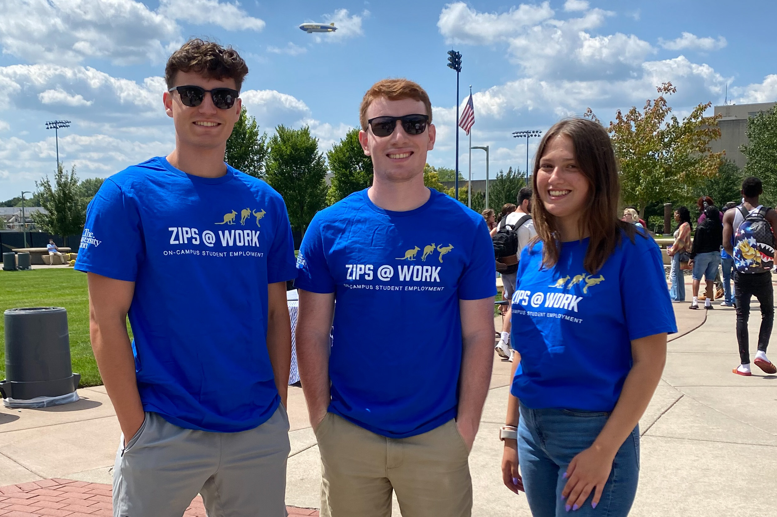 Three students stadning outside wearing Zips@Work t-shirts