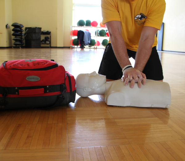 person perfoming CPR on a manikin in a class