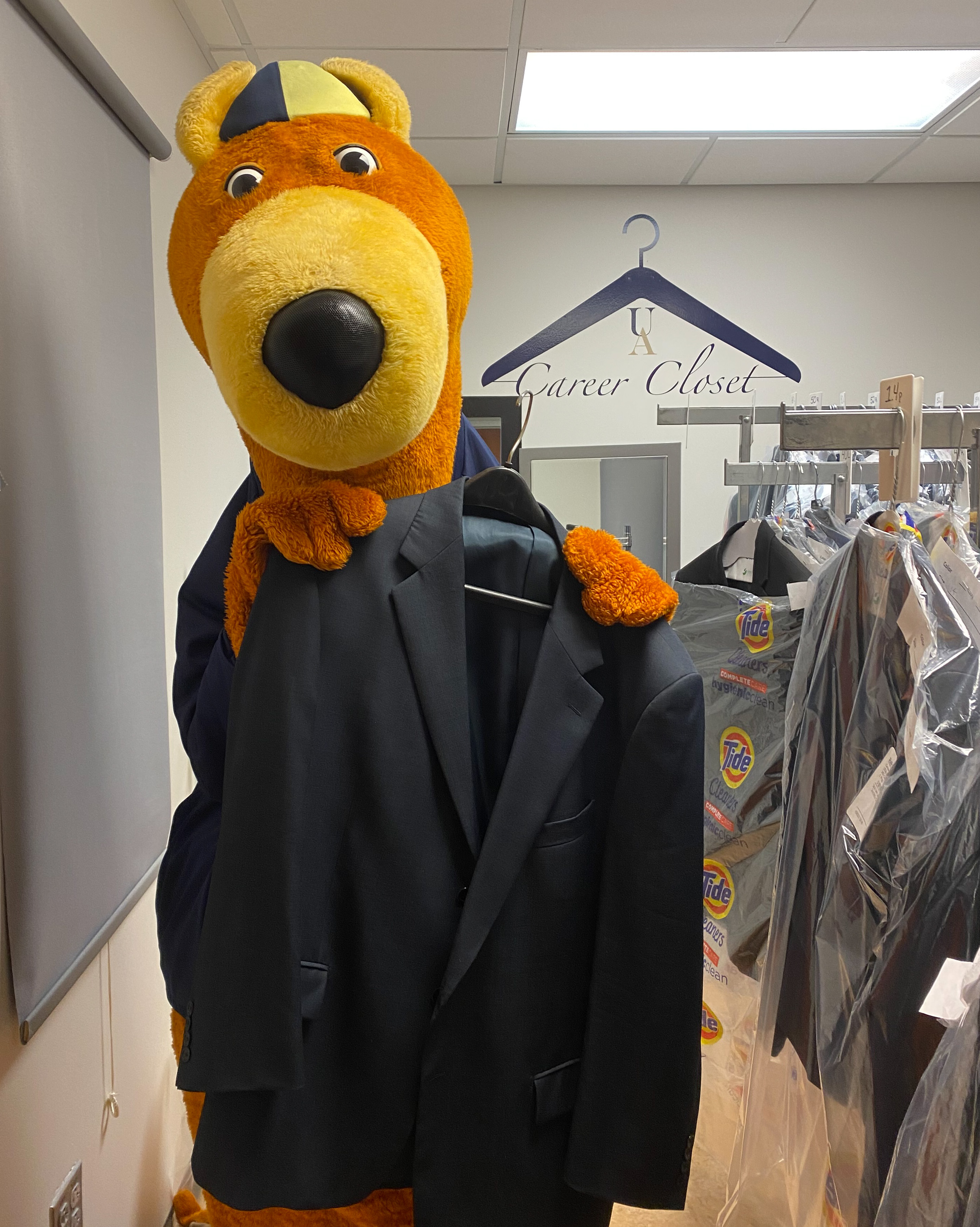Photo of Zippy holding a suit jacket in the Career Closet