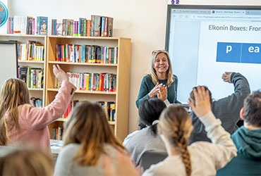 University of Akron faculty member leads an interactive classroom lesson as students raise their hands to participate.