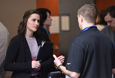 student speaks with a professional during a networking event, discussing internship and career opportunities