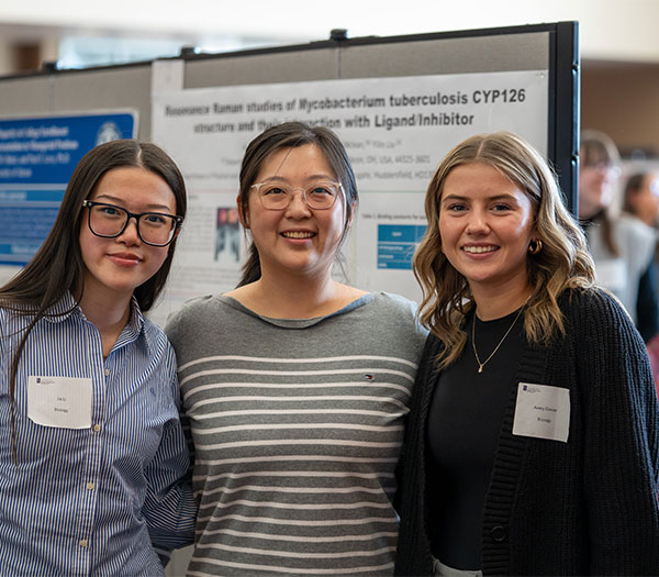 Three University of Akron students pose in front of a research poster during the Celebration of Undergraduate Research and Creativity.