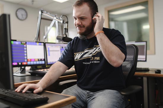 University of Akron male student sitting in radio DJ chair