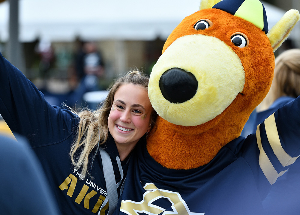 Excited University of Akron student hanging out with Zippy on campus.