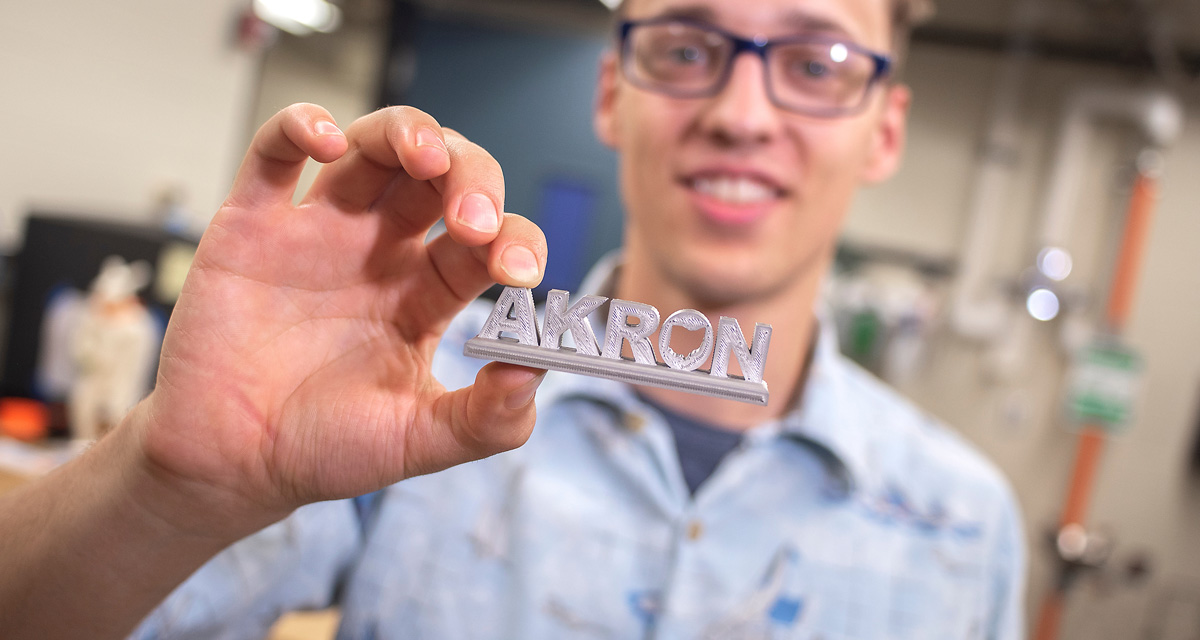 Student holding a 3D printed AKRON name plate